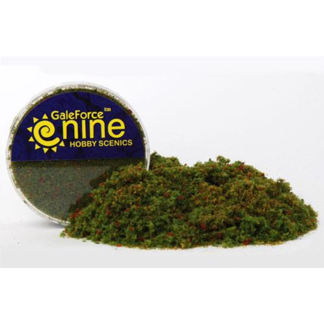 A transparent round container of Gale Force Nine Meadow Blend Flock showing a mix of vibrant green basing material for miniatures.