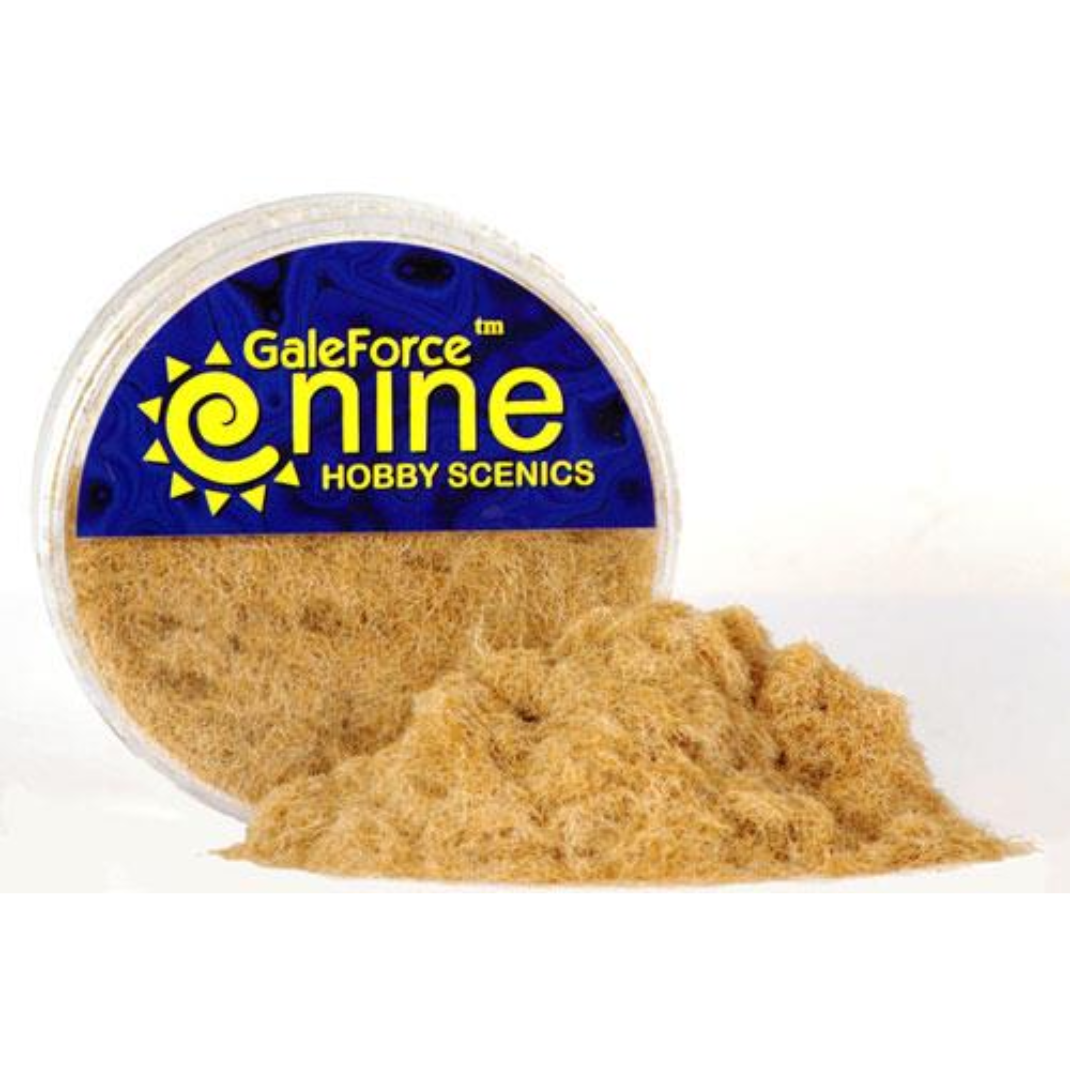 A transparent round container of Gale Force Nine Arid Static Grass showing the yellowed, dried-out basing fibres for miniature models.