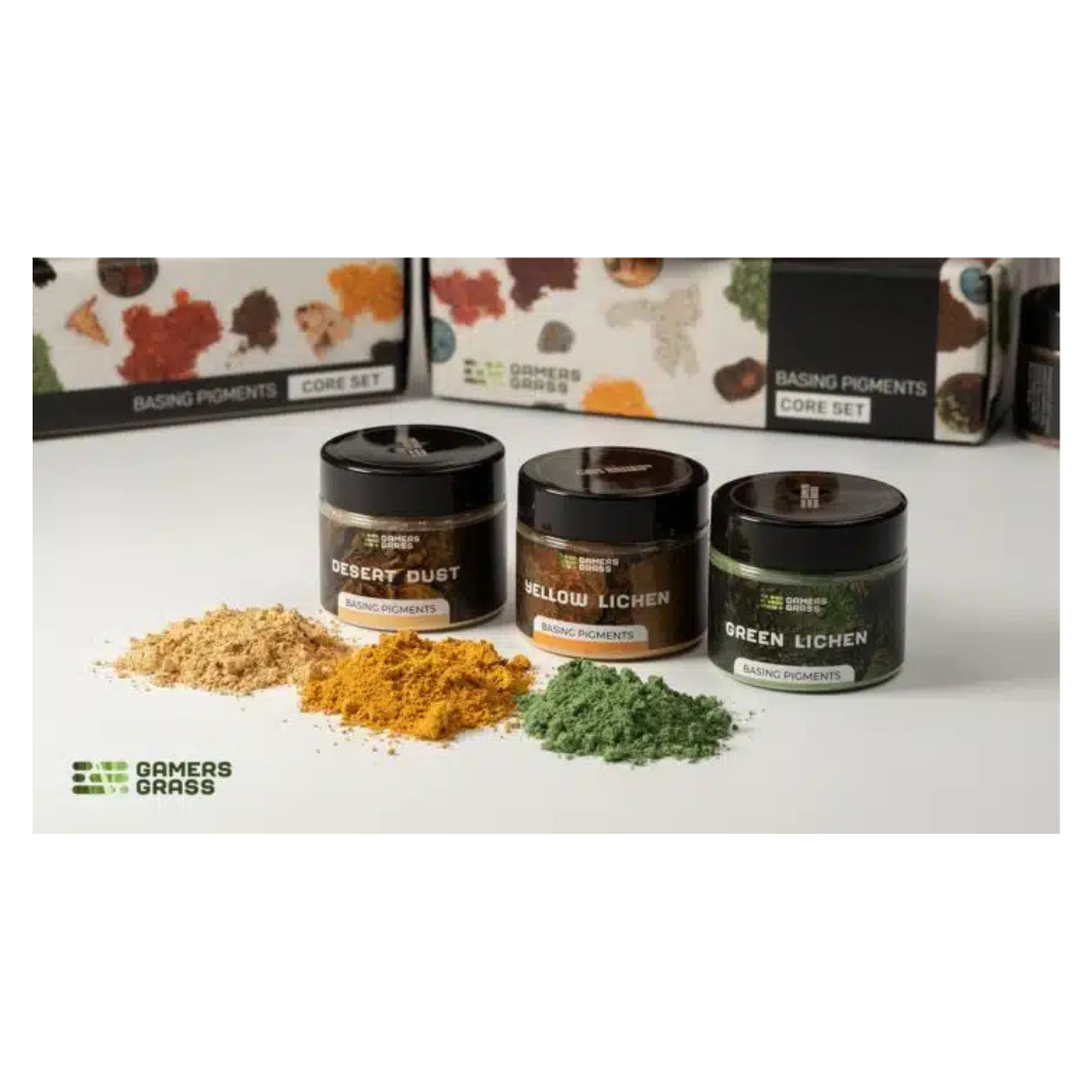 Three small containers of base pigments with visible contents on a white surface, with 'Gamers Grass' branding.